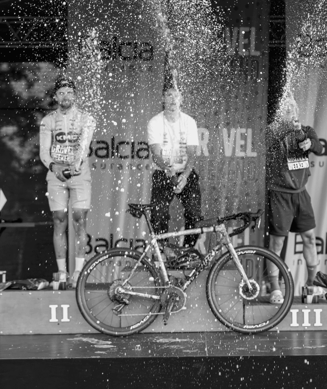 Athletes celebrating with champagne on a Gravel Weekend race podium.
